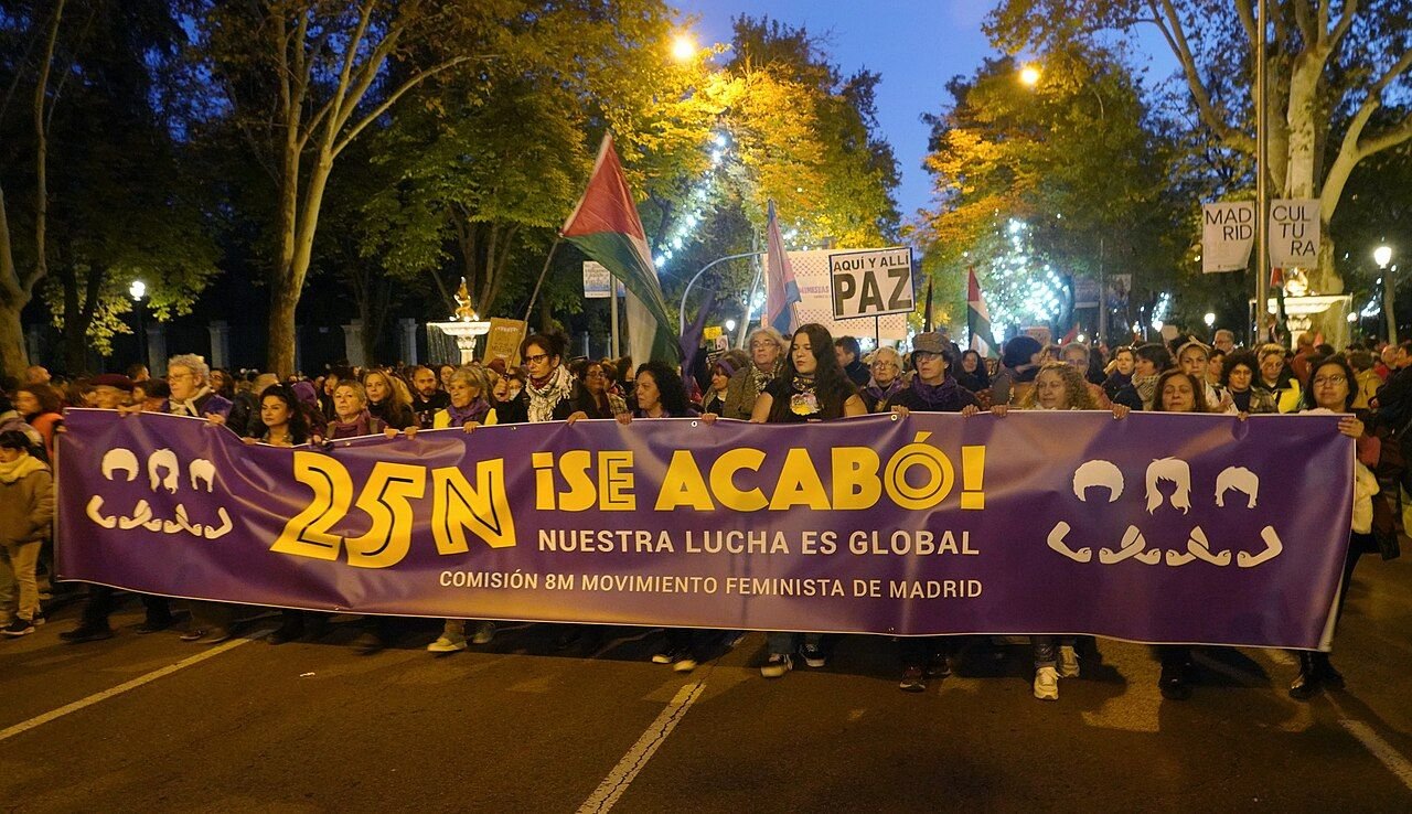 Pancarta morada «25N ¡Se acabó!» al anochecer en una manifestación feminista en Madrid