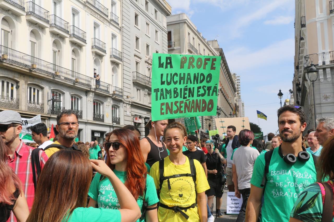 Una manifestante sostiene un cartel verde: «La profe luchando también está enseñando»
