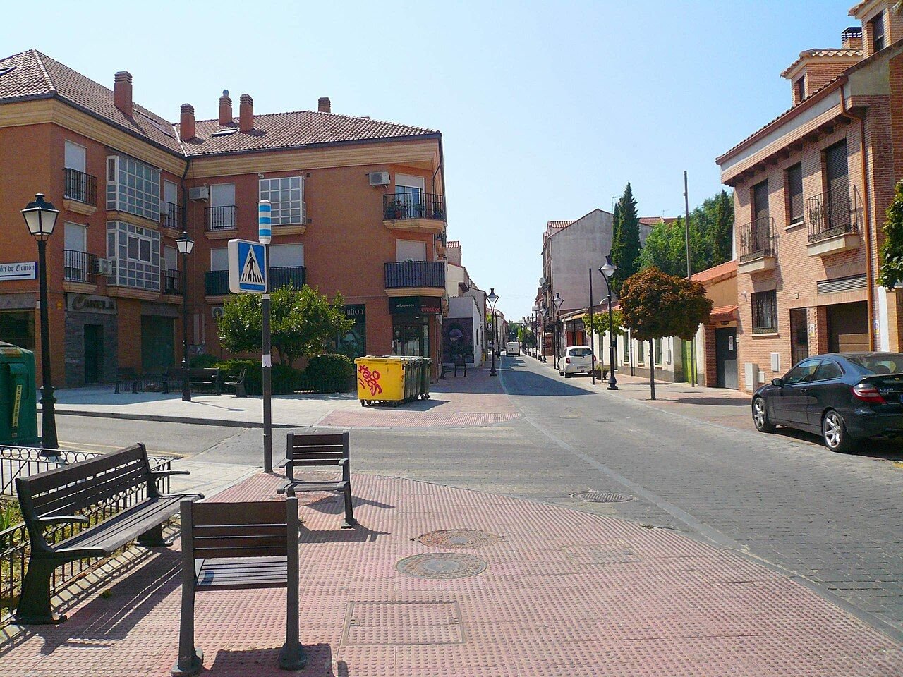 Calle de Griñón con bloques de viviendas de ladrillo y bancos