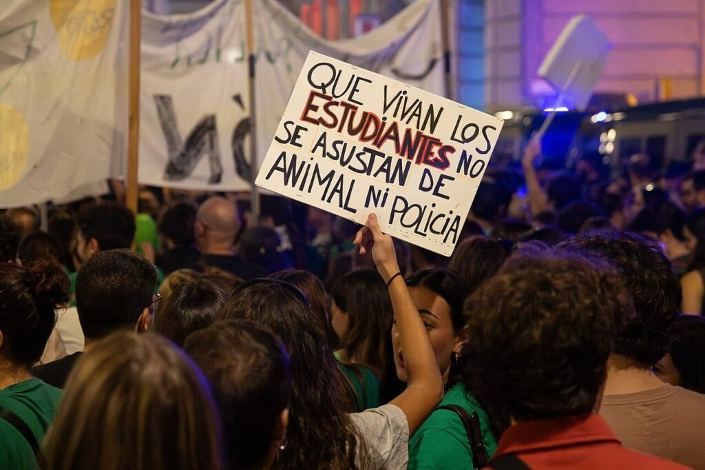Cartel escrito a mano en una manifestación nocturna: «Que vivan los estudiantes, no se asustan de animal ni policía»