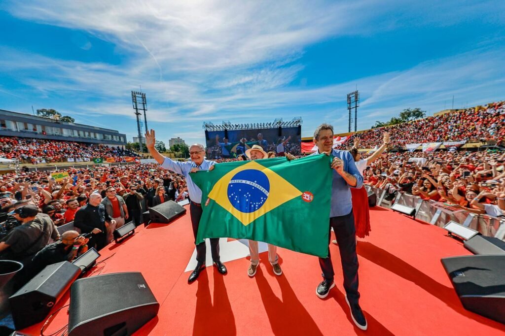 Lula da Silva sostiene una bandera de Brasil ante miles de simpatizantes en el lanzamiento de su campaña en 2026