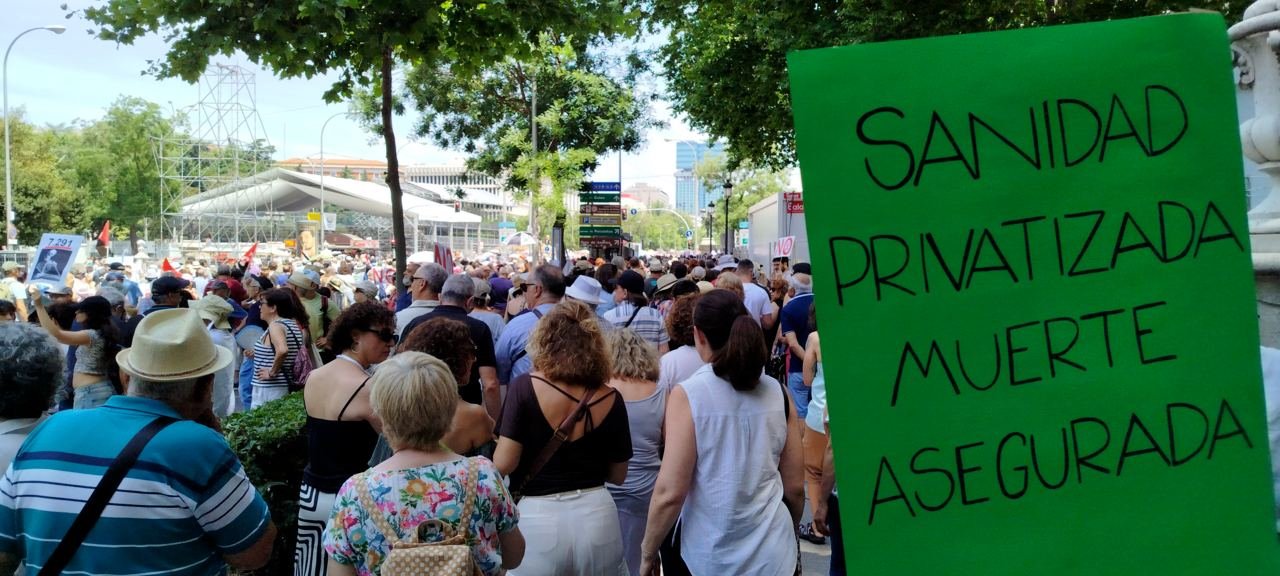 Manifestantes en Cibeles con un cartel verde que dice «Sanidad privatizada, muerte asegurada»