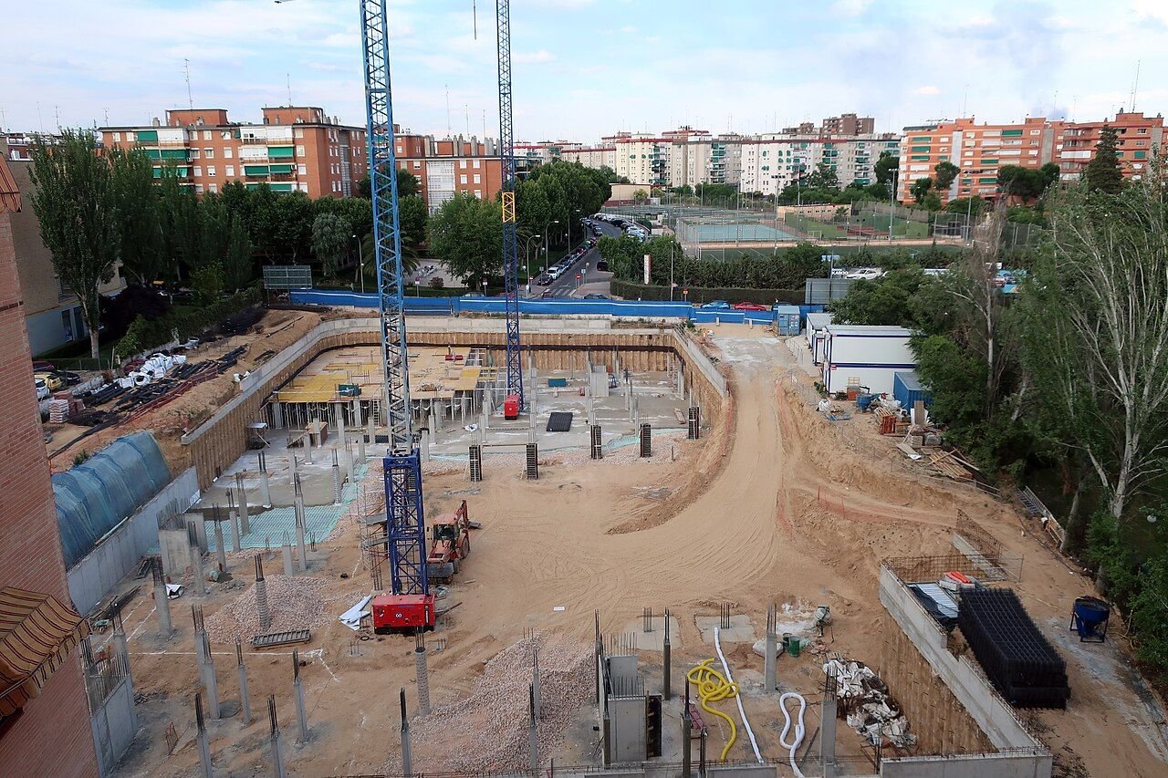 Solar en obras con grúas y bloques de viviendas al fondo en Móstoles