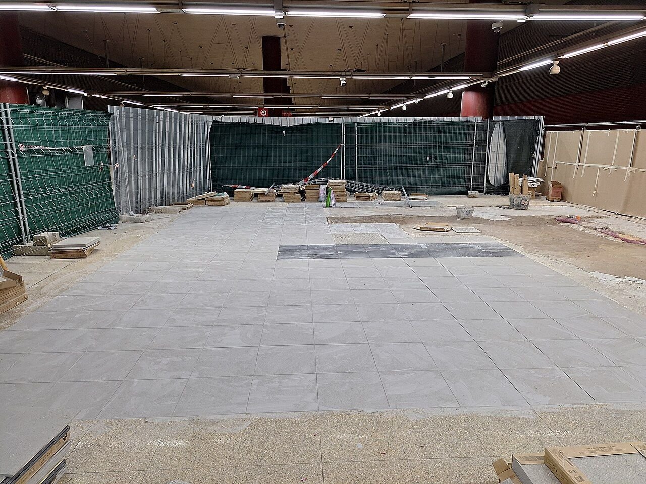 Vestíbulo de la estación de Cercanías de Getafe Centro en obras, con vallas y lonas verdes