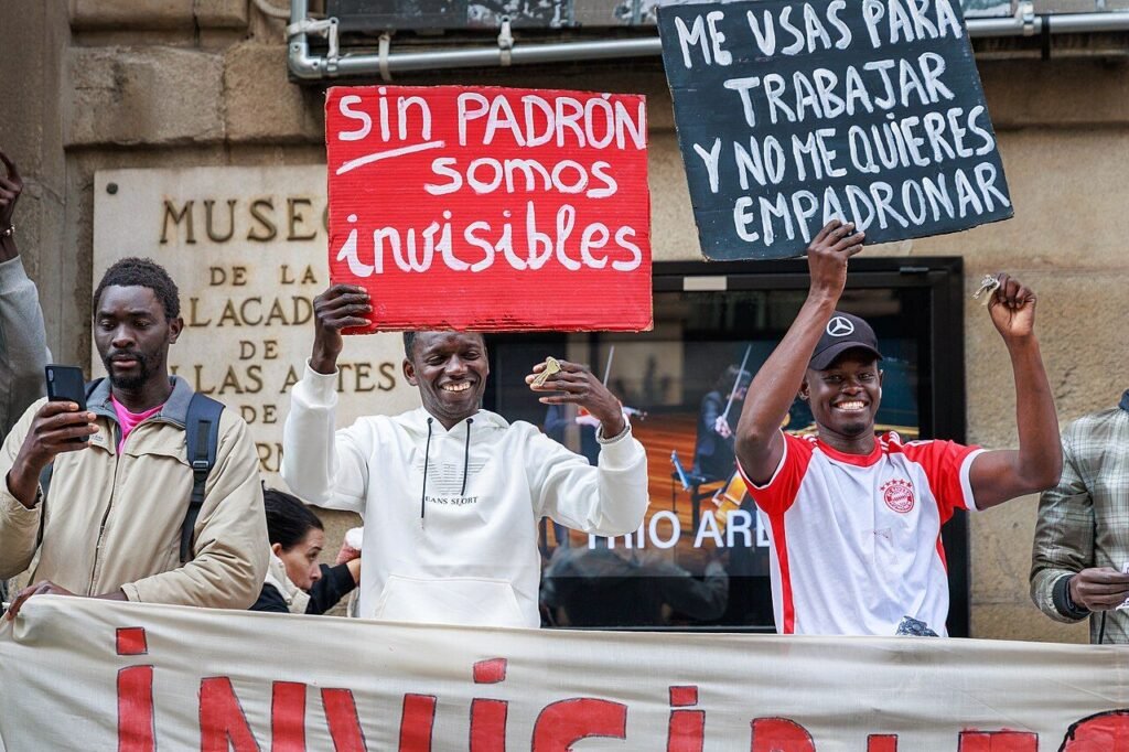 Manifestantes migrantes con carteles «Sin padrón somos invisibles» y «Me usas para trabajar y no me quieres empadronar»