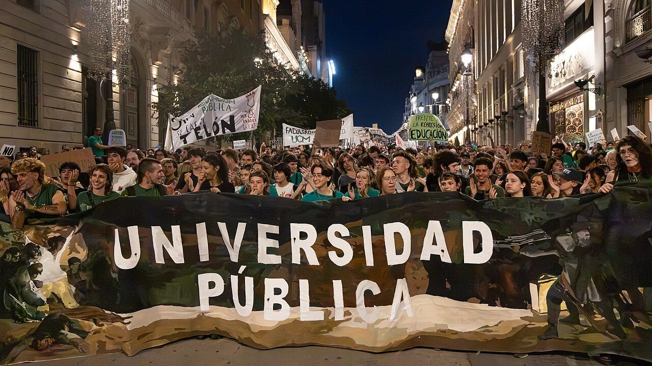Manifestantes de noche con una gran pancarta «Universidad pública» en la calle de Alcalá